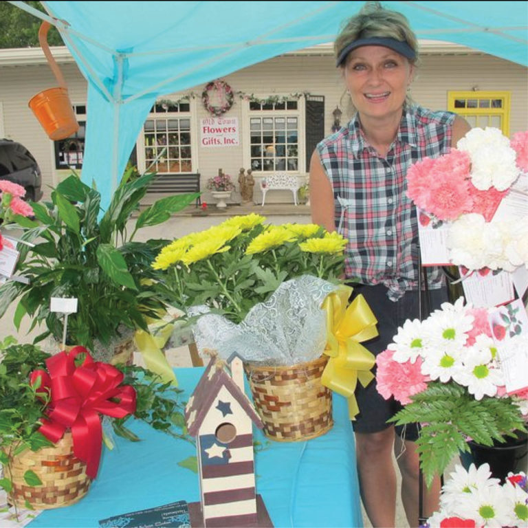 woman standing next to flowers under blue tent